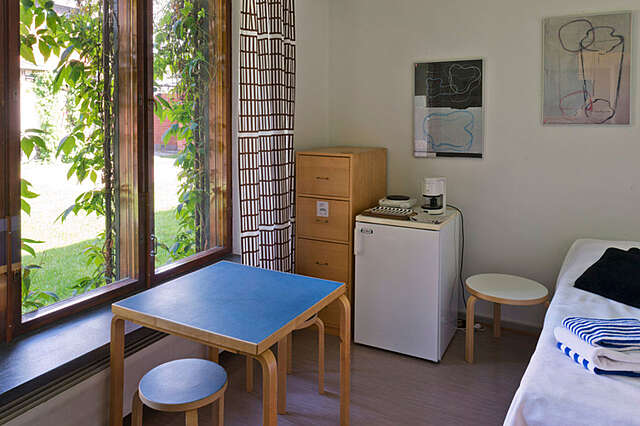 Room with Alvar Aalto's stool 60, a matching table, two posters of his sketches and other bedroom furniture.
