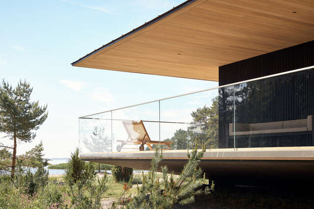 A wooden elevated deck with glass fencing. A sunbed is on the deck.