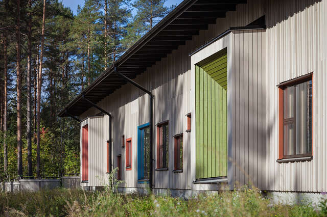 Facade wit wooden panels and colored window frames.
