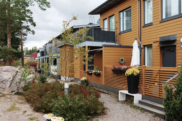 Orange wooden house with sand walkway and shrubbery in front.