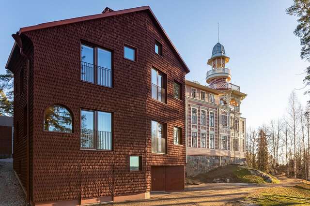 Large wooden building with red modern part in foreground and historical part in background.