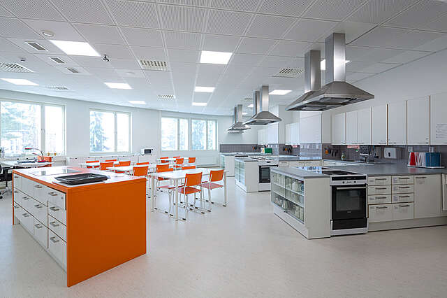 Classroom with a kitchen and tables.
