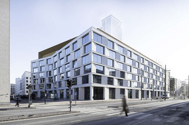 White building with large windows and a wooden top floor in a street crossing.