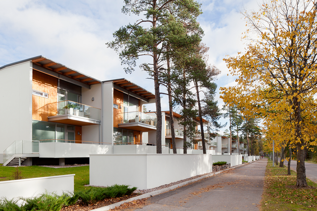 the facade of a white building. There are also pine trees