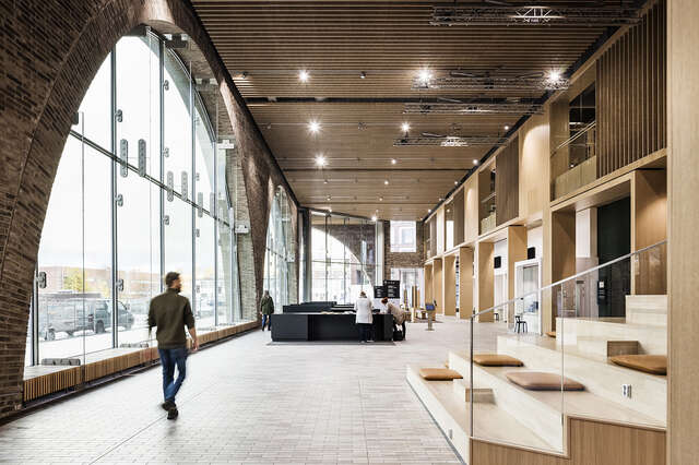 Interior photo of a space with a large arched window and wooden sitting chairs