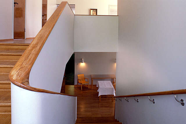 Wooden staircase with white walls and wooden railings.