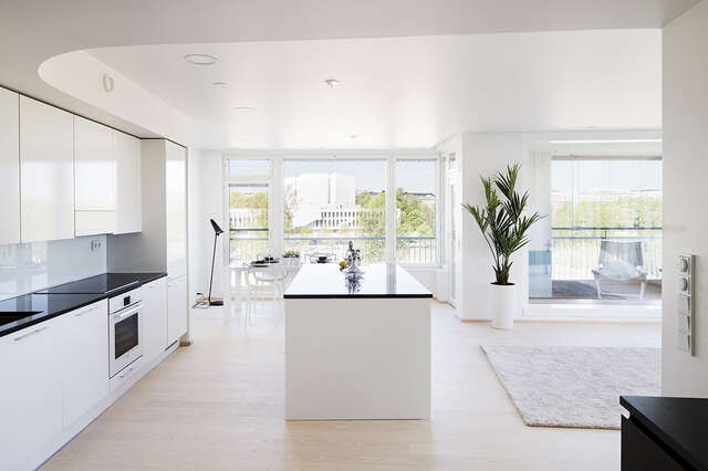 White spacious kitchen and dining room space next to the living room and glazed balcony.
