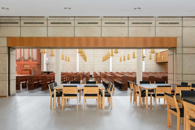 Groups of chairs and tables in a lower space opening towards a high space with pews