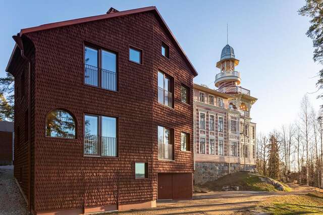 Large wooden building with red modern part in foreground and historical part in background.