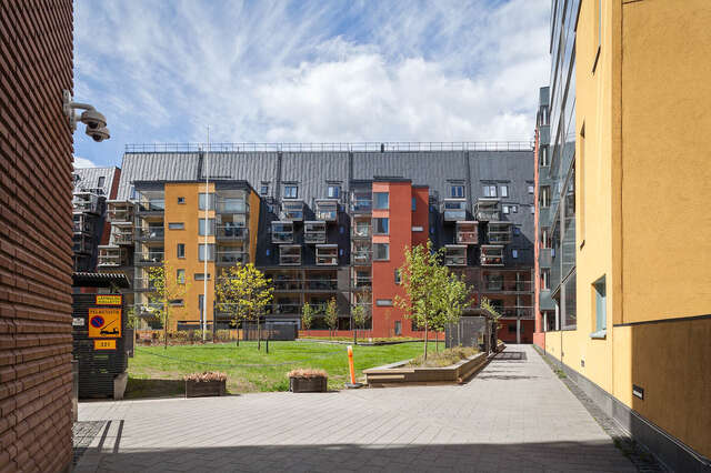 Apartment building with a mustard yellow and burnt orange plastered facade and a very slanted roof.