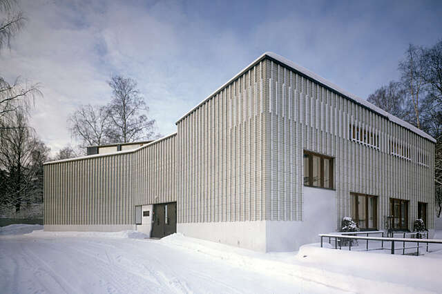 Grey and white facade with baton shaped glazed tiles and brown framed windows.