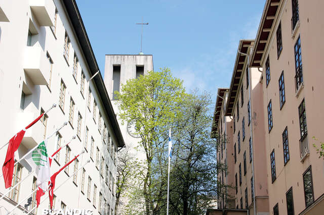 White multiple story building to the left and terra-cotta building to the right.