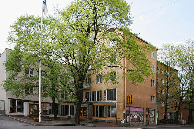 Yellow multiple story building with a protruding stone covered entrance.