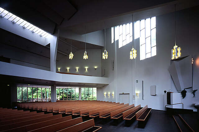 White interior with wooden benches and windows high up.