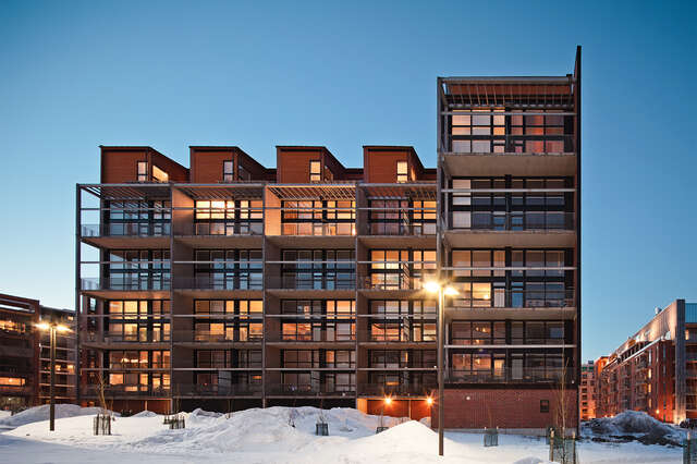 Multiple story apartment building with red bricks and large balconies.