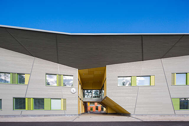 Facade with grey wood paneling and green window frames.