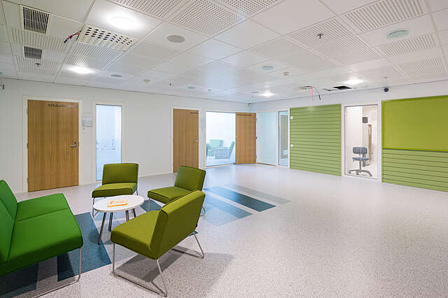 White room serving as a sitting area with green furniture and details.