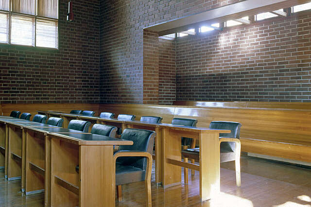 Brick interior with long wooden benches and rows of tables.