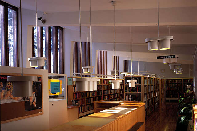 White interior with wooden bookshelves and hanging light fixtures.