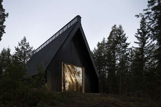 Evening photo, triangular dark building volume, light in the window