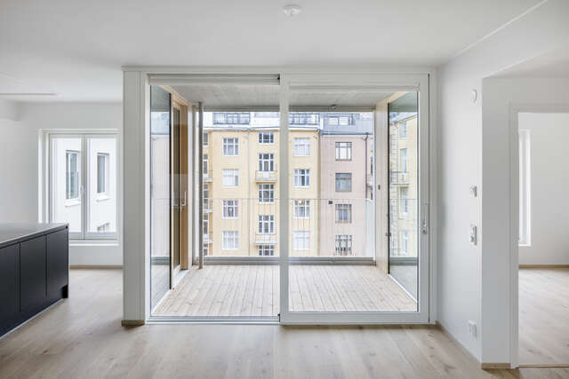A living room of an apartment building with glass doors leading to a balcony.