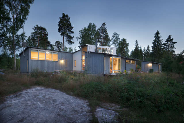 Wooden one-storey building in evening light surrounded by nature