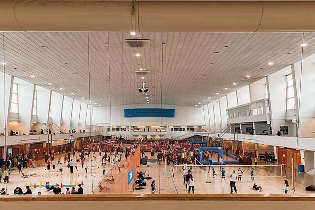 People playing different kinds of sports in a large white hall.