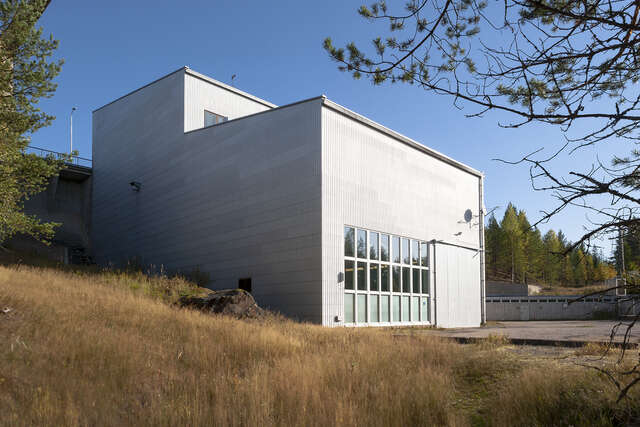 a Picture of a metal coloured hydropower plant in the summer.