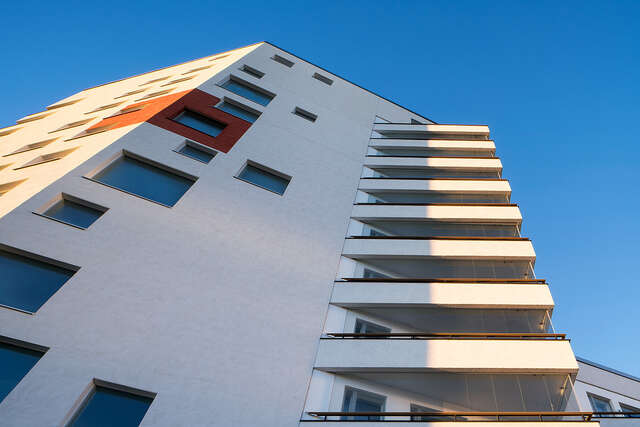 Building facade with offset differently sized windows on the left, at the right there are triangular balconies protruding at an angle.
