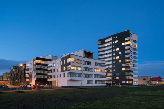 Multiple storey apartment buildings with no straight lines, black and white plastered walls and long balconies at the sides.