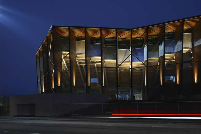 Wooden building with glass walls illuminated at night.