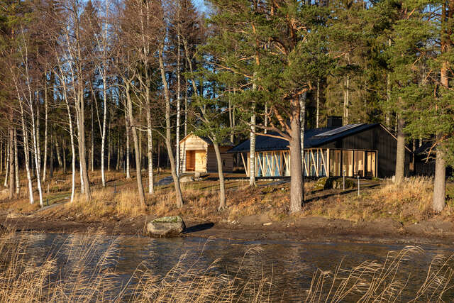 Wooden house on lake shore with trees.