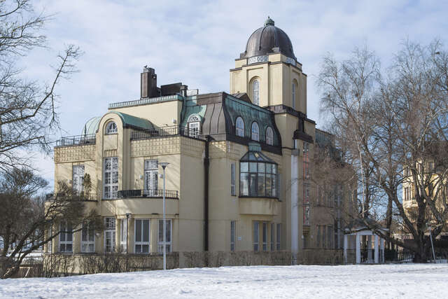 Yellow facade with white framed windows, arch details and a cupola.