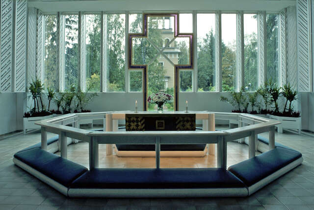 Altar with a window behind it. In the window there is a purple cross detail made out of stained glass.
