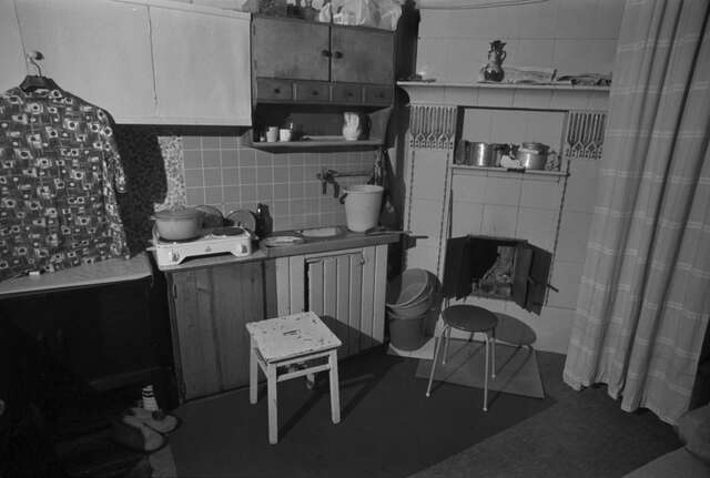 Black and white picture of a kitchen with a portable stove and a fireplace.