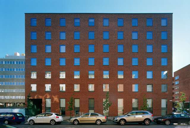 Façade of a seven-storey red brick building with square windows