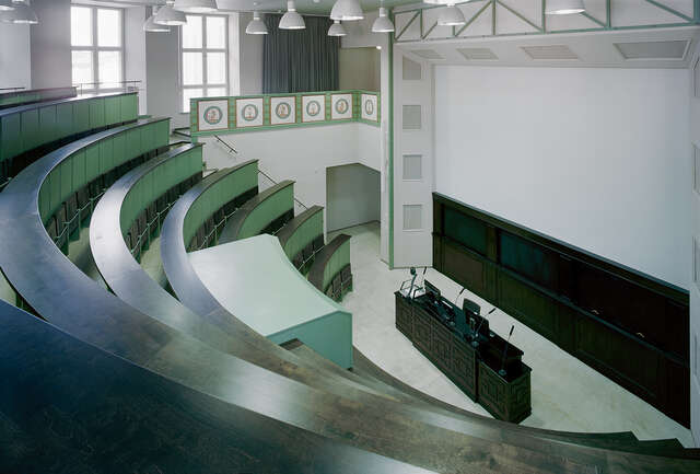 Amphitheatre-like auditorium with green seats and white hanging lights