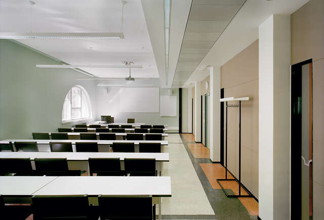 Classroom with arch window, table and chair rows and screen