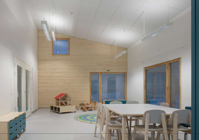 Room with a table and toys, rear wall clad with timber