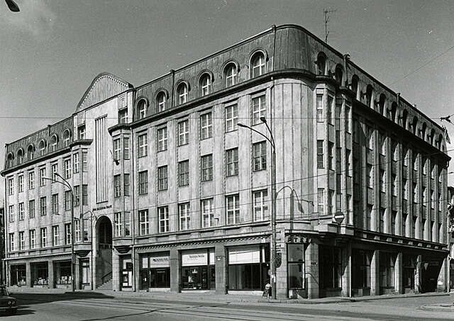 Old black and white picture of a multiple story house with grid windows and arch details.