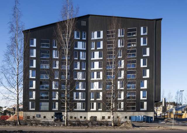 Black apartment building with eight stories and the facade sides looking at each other at an angle.