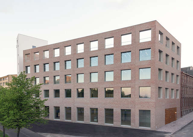 Large brick building with five floors and square shaped symmetrical windows.