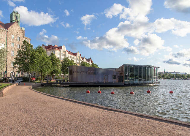 Front facade with a copper panels leading to the entrance and the glass walls of the restaurant looking at the sea.