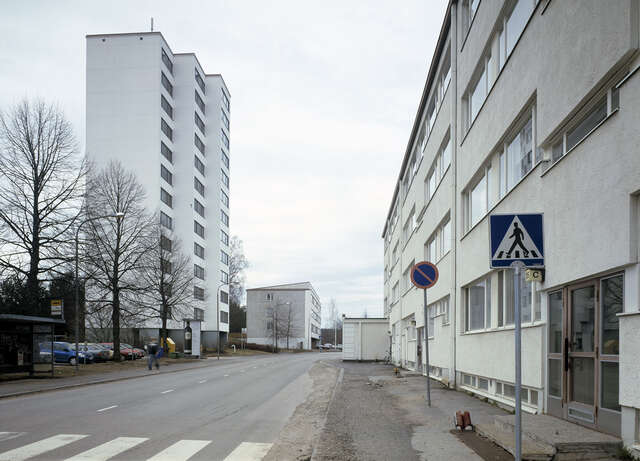 Tall white building to the left of the street, on the right there is a smaller four story residential building.