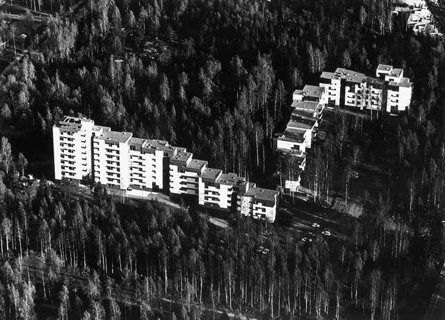 Aerial image of a white apartment block surrounded by forest.