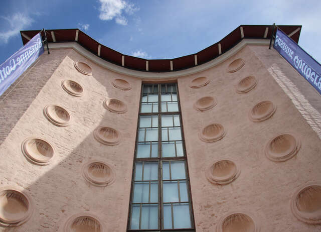 Round medallions on the curved facade above the entrance. In the middle there is a long grid window.