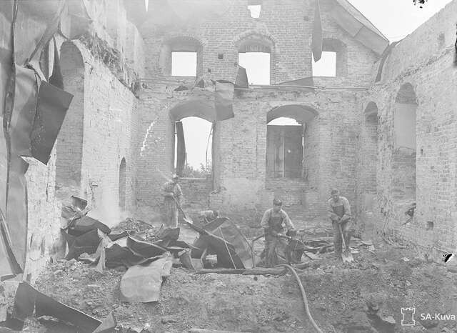 Three young men working in the destroyed castle in a black and white picture.