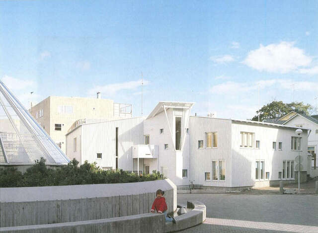 Wooden white painted daycare centre and a square in front of it