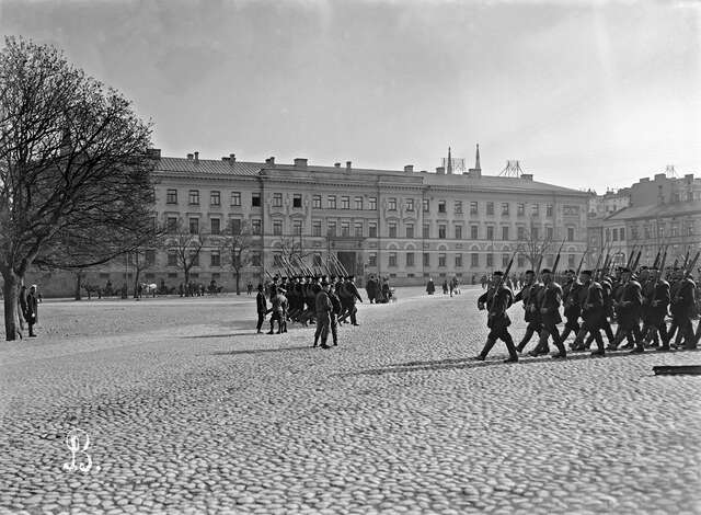 Soldiers marching on a public square.