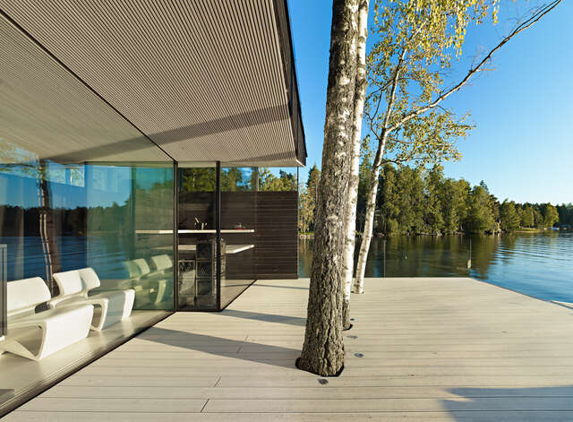 Trees growing from terrace holes in front of glass façade and light-coloured canopy